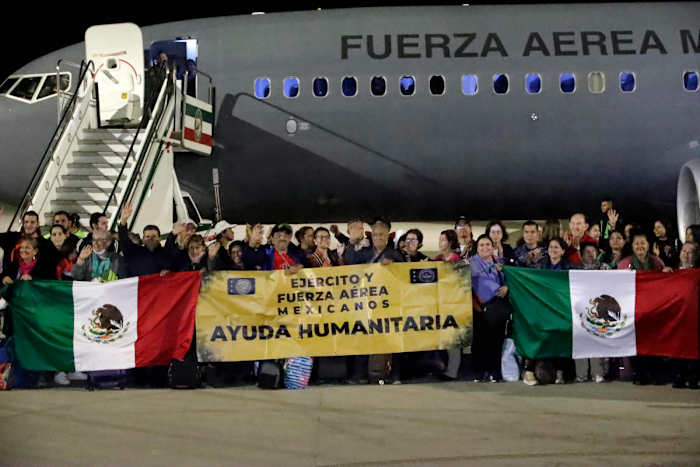 Mexicanos repatriados de Israel sostienen bandera de México y manta